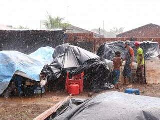 Com o início da chuva, Wanderson de Souza (ao centro) tentou cobrir os pertences da família. (Foto: Marcos Ermínio)