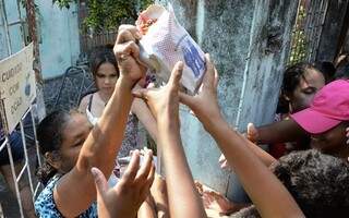 Moradora distribui pacotes preparados para a festa. (Foto: Anderson Gallo/Diário Corumbaense)