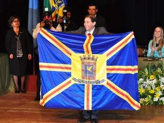 Alcides Bernal e a bandeira de Campo Grande, na solenidade de posse. (Foto: Luciano Muta)