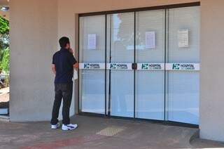 Morador lê comunicado afixado na porta do hospital, que pode suspender todos os atendimentos devido ao atraso no pagamento feito pelo Evangélico (Foto: Eliel Oliveira)