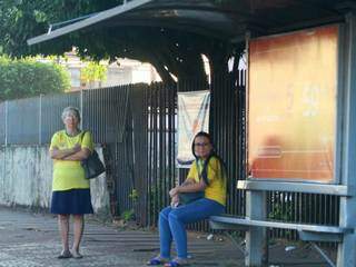 De verde e amarelo, trabalhadores esperam pelo transporte em ponto de ônibus da Capital  (Foto: Saul Schramm)