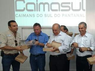 Ministro Blairo Maggi (de azul), Pedro Chaves e Reinaldo Azambuja recebem artigos produzidos com couro de jacaré. (Foto: Priscilla Peres)