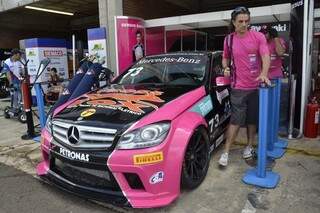 Carro combina rosa pink com preto. Integrantes da equipe usam a camiseta rosa, com orgulho.