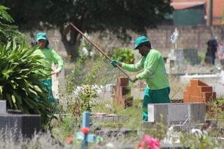 Funcionários da prefeitura tiram o mato em volta dos túmulos do Cruzeiro. (Foto:Marcos Ermínio) 