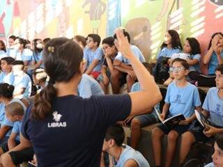 O aluno surdo, Luigi Fuchs, assisti palestra de escritora Ariadne Cantú no ginásio da Escola Municipal Antônio José Paniago (Foto: Paulo Francis)