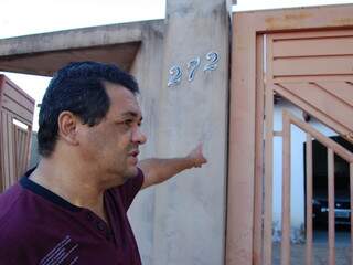 Morador mostra que portão já está afastado do muro, consequência da raiz do pé danificando a estrutura da casa. (Foto: Simão Nogueira)
