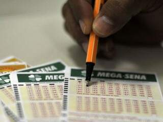 Apostador escolhendo números para marcar em cartela da Mega-Sena (Foto: Marcello Casal Jr./Agência Brasil)
