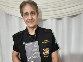 O agente penitenciário Gilberto Avelino Mendes segurando o livro de crônicas que lançou (Foto: Arquivo Pessoal)