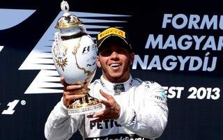 O piloto inglês ergue seu primeiro troféu pela Mercedes no GP da Hungria. (Foto: AFP)