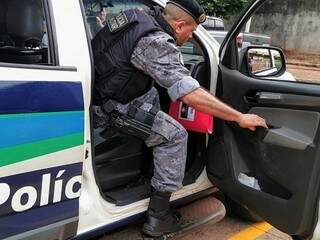 Com pasta do Gaeco na mão, policial da Força Tática chega à delegacia da Polícia Civil, em Dourados (Foto: Adilson Domingos)