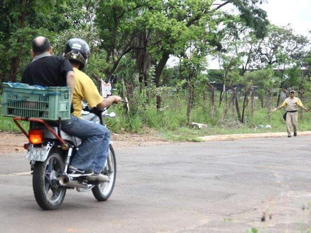 Condutor com garupa sem capacete &quot;d&aacute; de cara&quot; com agente de tr&acirc;nsito em rua