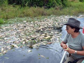 Moradora observa peixes mortos nas margens do rio Negro. (Foto: Rhobson T. Lima/site O Pantaneiro)