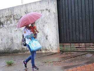 Mulher protege bebê com guarda-chuva, que tirou do armário após 42 dias (Foto: Marina Pacheco)