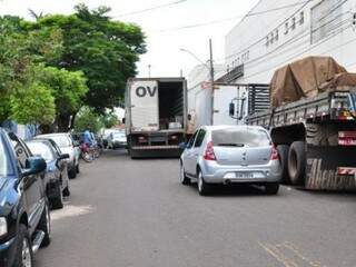 De um lado caminhões estacionados; de outro, carros e motos. No meio, automóveis esperam para passar enquanto outro caminhão faz descarga. (Foto: Luciano Muta)