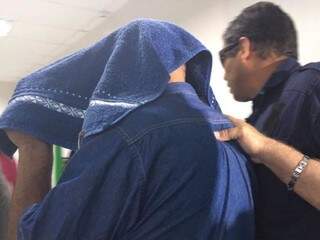 Com rosto coberto, policial chega à delegacia para prestar depoimento sobre morte de mulher. (Foto: Julia Kaifanny)