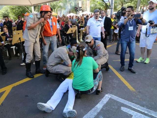 Com sombrinhas e muita &aacute;gua, plateia disputa sombra para ver desfile