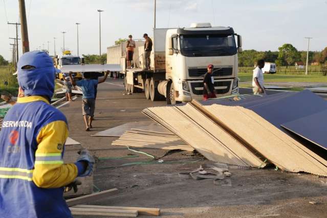 Carga de madeirite fica espalhada ap&oacute;s carreta tombar ao fazer curva na BR-163