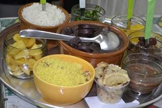 O prato inclui farofa, torresmo, vinagrete, mandioca e banana frita, arroz, couve e laranja.