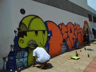 Artistas grafitando uma das parede de Dourados. (Foto: Joandra Alves)