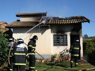 Bombeiros apagando fogo na residência de idosa (Foto: Saul Schramm)