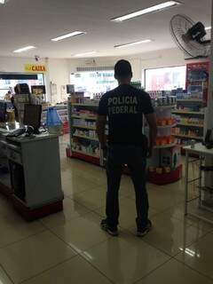Agente da Polícia Federal cumprindo mandado de busca e apreensão em farmácia de Caarapó (Foto: Divulgação)