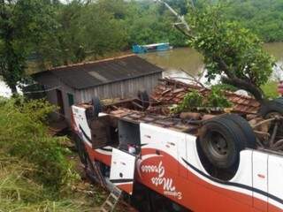 Ônibus parou com rodas para cima ao cair em ribanceira e atingir casa de madeira (Foto: O Pantaneiro) 