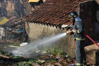 Bombeiros combatem fogo que começou em vegetação e lixo nos fundos do imóvel. (Foto: Ângela Kempfer)