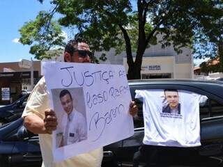 Motorista de aplicativo segura cartaz durante protesto nesta manhã em Campo Grande, cobrando a prisão do assassino de Rafael Baron. (Foto: Henrique Kawaminami)