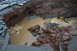 Carro ficou totalmente submerso em cratera na rua Panambi Vera, em Campo Grande (Foto: Simão Nogueira)