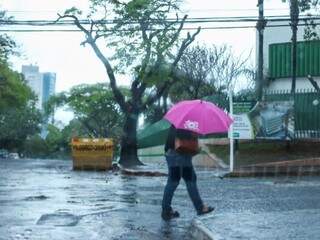 Nesta manhã mulher se protege da chuva que cai desde ontem em Campo Grande  (Foto: Henrique Kawaminami) 