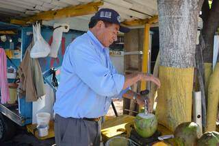 Ele furando o coco para vender (Foto: Alana Portela)