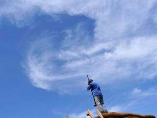 Pedreiro aproveita o tempo aberto para trabalhar no telhado de casa no Tiradentes; céu permanece com poucas nuvens no fim de semana (Foto: Alcides Neto/Arquivo)