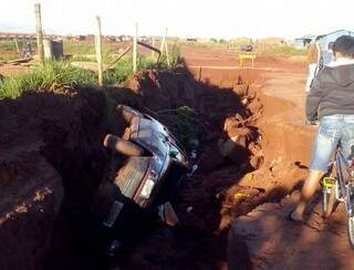 Fiat Uno caiu em buraco de dois metros de profundidade aberto pela enxurrada em Naviraí (Foto: Umberto Zum/Tanamidianavirai)
