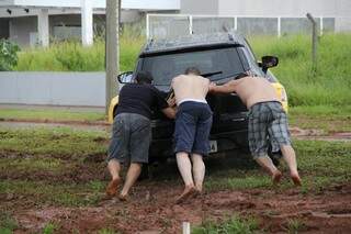 Amigos ajudam motorista que ficou atolada no canteiro central da Avenida Mato Grosso. (Foto: Marcos Ermínio)