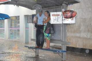 Casal protege-se da chuva na avenida Afonso Pena (Foto: Vanderlei Aparecido)