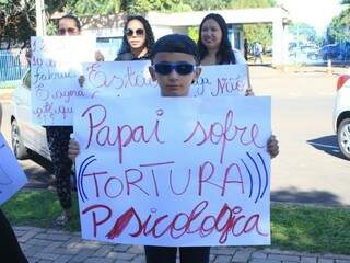 Criança segura cartaz com a frase: Papai sofre tortura psicológica (Foto: Marina Pacheco) 