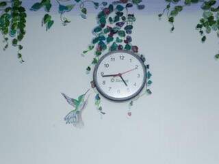 Beija-flor interagindo com o relógio que recebeu flores coloridas ao entorno (Foto: Kisie Ainoã)