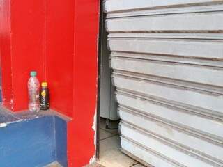 Porta da farmácia foi danificada por assaltantes. (Foto: Henrique Kawaminami)