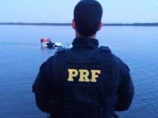 Policial rodoviário federal as margens do rio Paraná observando ação de retirada de droga (Foto: Assessoria de Comunicação)
