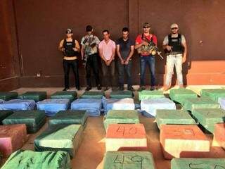 Fardos de cocaína e dois dos três traficantes ao lado de agentes da Senad (Foto: Divulgação)