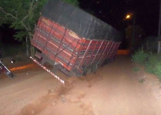 Caminh&atilde;o carregado de madeiras fica preso em valeta de estrada de terra