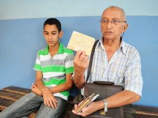 Gabriel e o pai, que mostra carteiras de trabalho para dar exemplo ao filho. (Foto: Rodrigo Pazinato)
