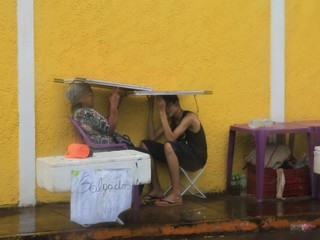 Em tarde de &#039;vai e volta&#039; de chuva, vendedores tentam se proteger da água em Campo Grande. (Foto: Marina Pacheco).