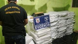 Agente da Senad observa fardos de maconha encontrados em casa em Pedro Juan Caballero (Foto: Leo Veras)