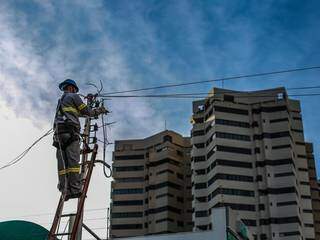 Técnico prestador de serviço da Energisa realiza a reposição de fios que foram furtados no centro de Campo Grande, no dia 11. (Foto: Fernando Antunes)