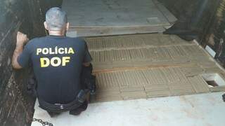 Policial observa tabletes de maconha em fundo falso na carroceria de carreta (Foto: Divulgação)