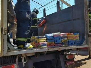Bombeiros retiram tabletes de cocaína de fundo falso de carreta, hoje em Dourados (Foto: Adilson Domingos)