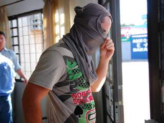 Acusado do crime esconde o rosto ao sair da delegacia, após prestar depoimento. (Foto: Simão Nogueira)
