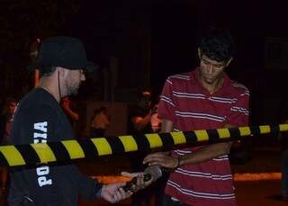 Isaque Daniel Gonçalves Baptista, um dos assaltantes, recebe arma de policial para participar da reconstituição do crime (Foto: Sidney Bronka/94 FM)
