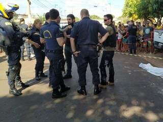 Guardas e policiais ao lado do corpo, sábado, na Vila Cachoeirinha, em Dourados; corporação vai abrir sindicância para investigar o caso (Foto: Adilson Domingos)